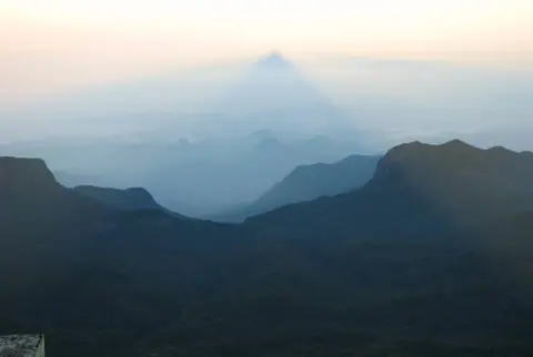 The triangular shadow of Sri Pada cast over the hills at sunrise