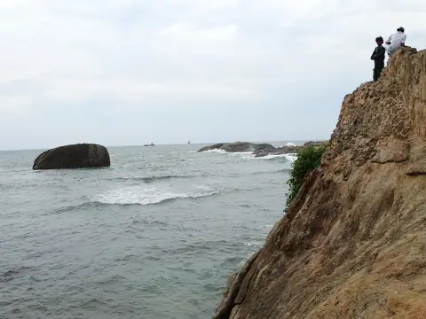 People on the rocky bastion where the Galle Fort ramparts meet the sea