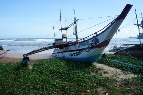 A painted outrigger fishing canoe on the beach at Weligama