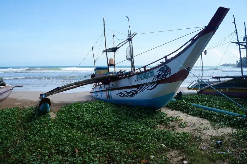 A painted outrigger fishing canoe on the beach at Weligama